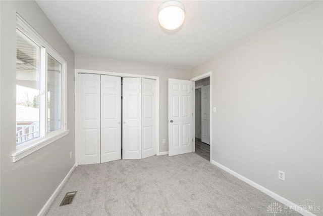 unfurnished bedroom with light colored carpet and a closet