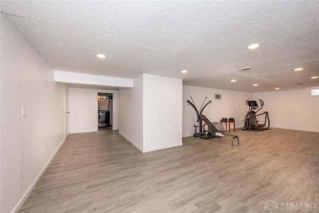 workout area with light hardwood / wood-style floors and a textured ceiling