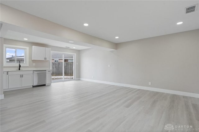 unfurnished living room featuring sink and light hardwood / wood-style flooring