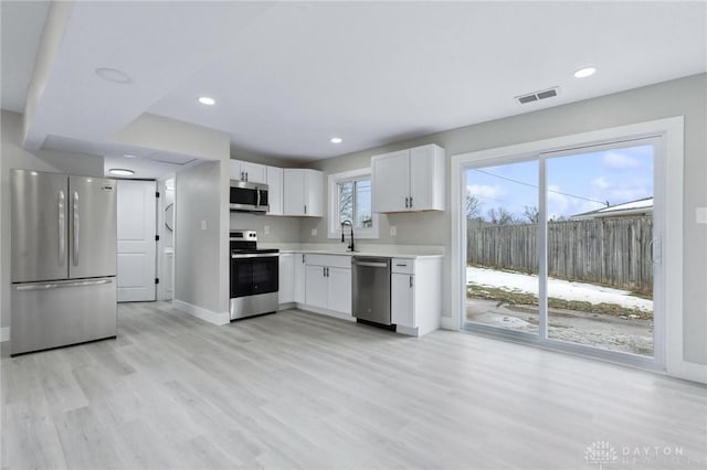 kitchen featuring white cabinetry, sink, light wood-type flooring, and appliances with stainless steel finishes