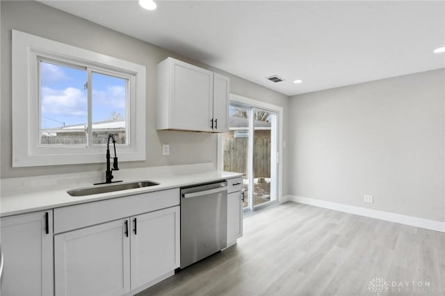 kitchen with white cabinetry, sink, stainless steel dishwasher, and light wood-type flooring