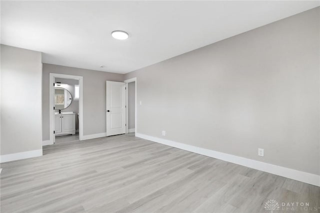 unfurnished bedroom featuring ensuite bath and light wood-type flooring