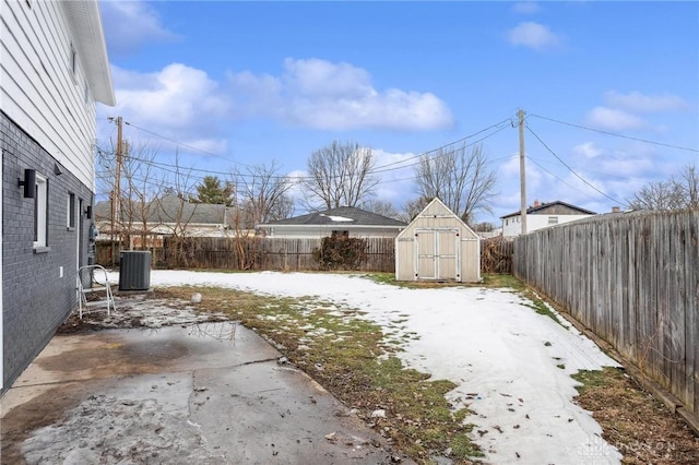 yard layered in snow featuring a shed, cooling unit, and a patio