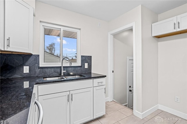 kitchen featuring light tile patterned flooring, sink, white cabinetry, dark stone countertops, and decorative backsplash