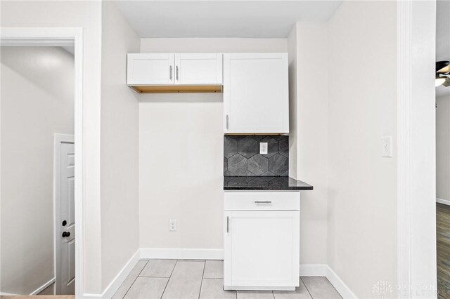 kitchen featuring tasteful backsplash, light tile patterned floors, and white cabinets