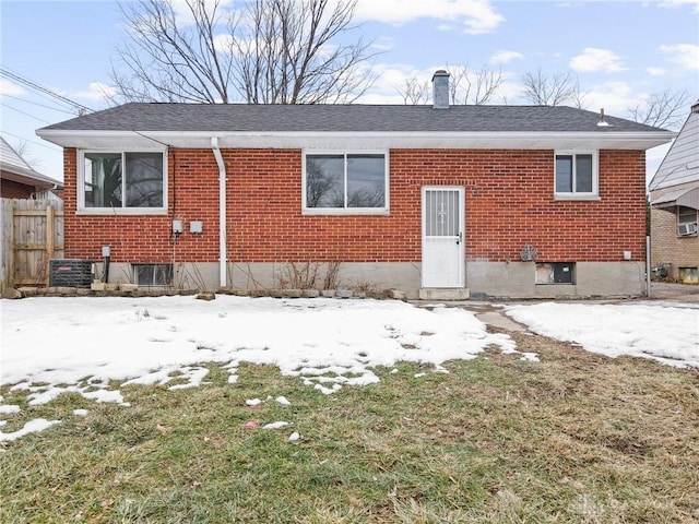 snow covered property with central AC unit and a yard