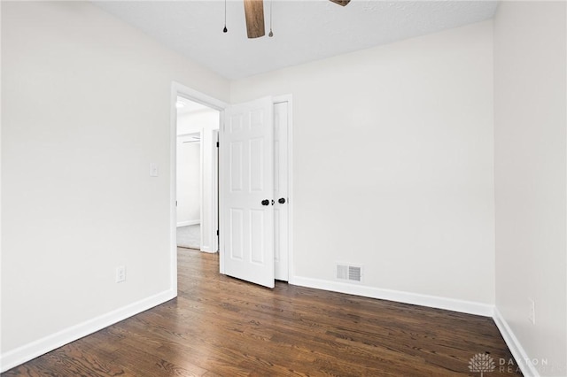 spare room with dark wood-type flooring and ceiling fan