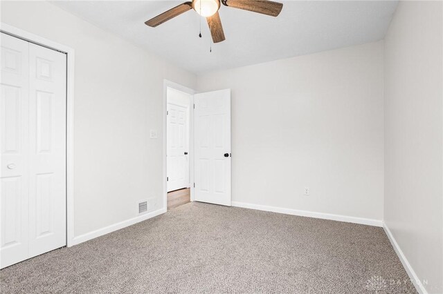 unfurnished bedroom with ceiling fan, carpet flooring, and a closet