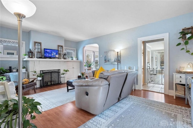 living room featuring a brick fireplace and wood-type flooring