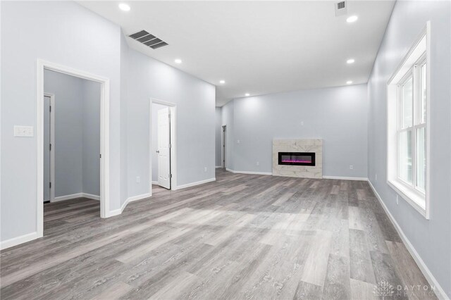 unfurnished living room with a high end fireplace and light wood-type flooring