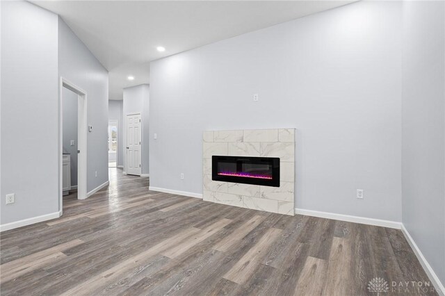 unfurnished living room featuring a tile fireplace and wood-type flooring