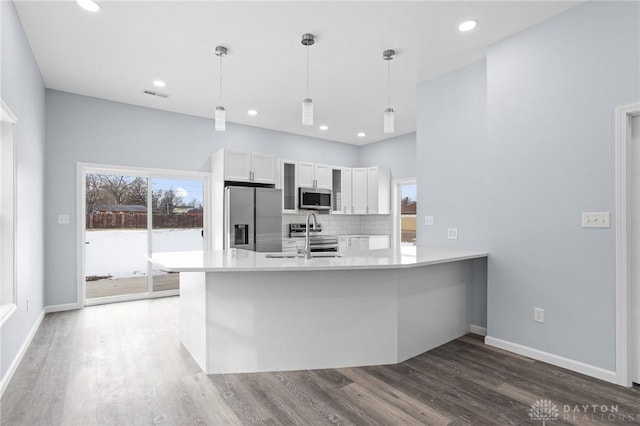 kitchen featuring appliances with stainless steel finishes, tasteful backsplash, white cabinetry, hanging light fixtures, and kitchen peninsula