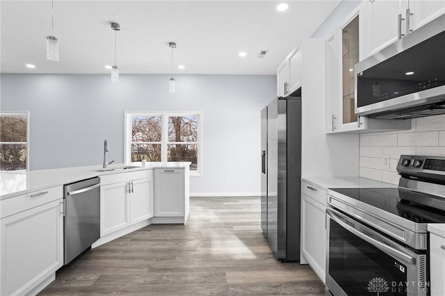 kitchen featuring backsplash, stainless steel appliances, decorative light fixtures, and white cabinets