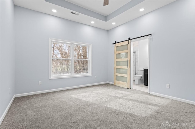 carpeted spare room featuring a barn door and ceiling fan