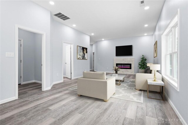 living room featuring a high end fireplace and light wood-type flooring