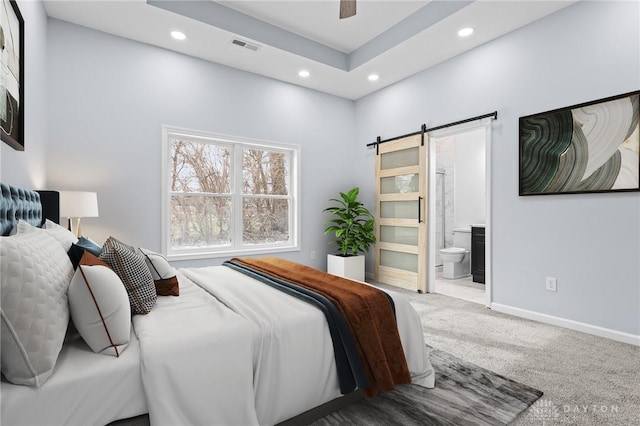 bedroom featuring connected bathroom, a barn door, ceiling fan, and carpet flooring