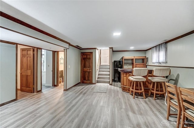 kitchen featuring crown molding, a breakfast bar, and light hardwood / wood-style floors