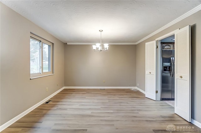 empty room featuring ornamental molding, a chandelier, and light hardwood / wood-style flooring