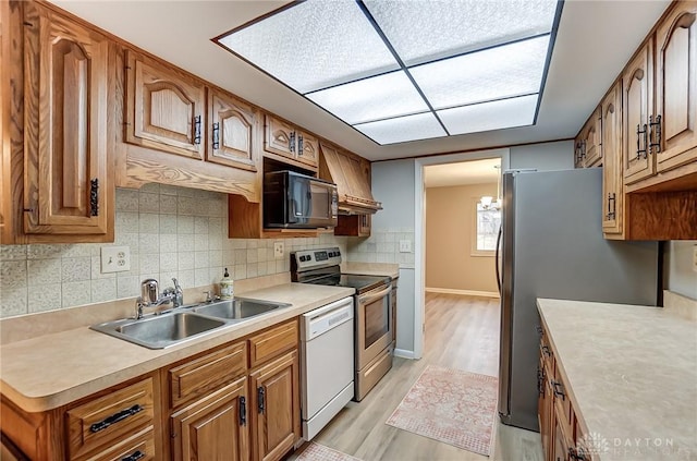 kitchen with tasteful backsplash, sink, light hardwood / wood-style floors, stainless steel appliances, and custom range hood