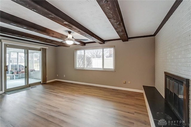 unfurnished living room with wood-type flooring, a brick fireplace, and plenty of natural light