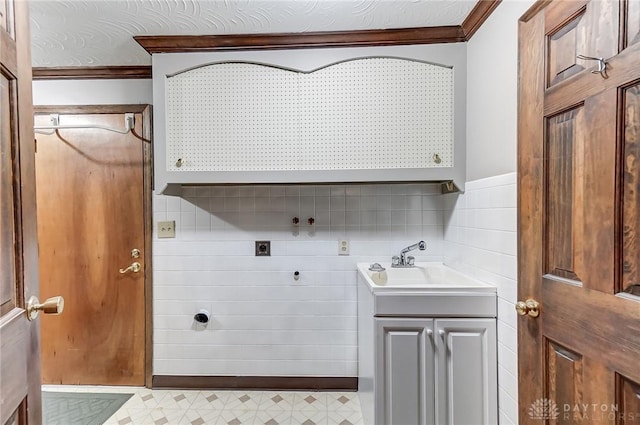 clothes washing area with cabinets, ornamental molding, electric dryer hookup, and sink