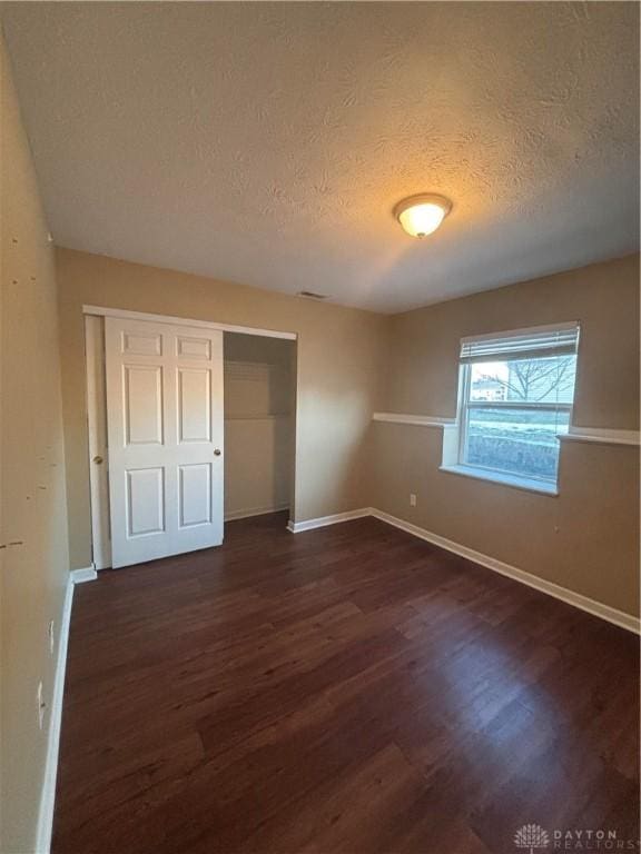 unfurnished bedroom featuring dark hardwood / wood-style floors, a closet, and a textured ceiling