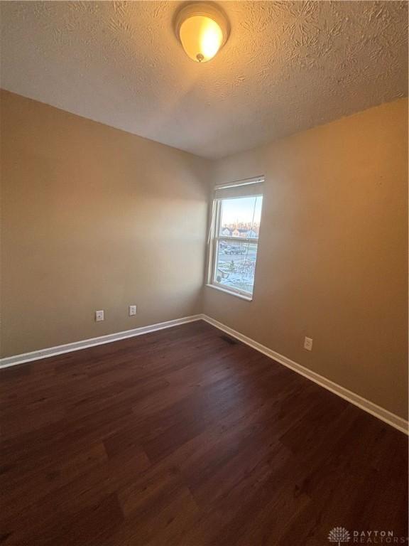 spare room with dark hardwood / wood-style floors and a textured ceiling