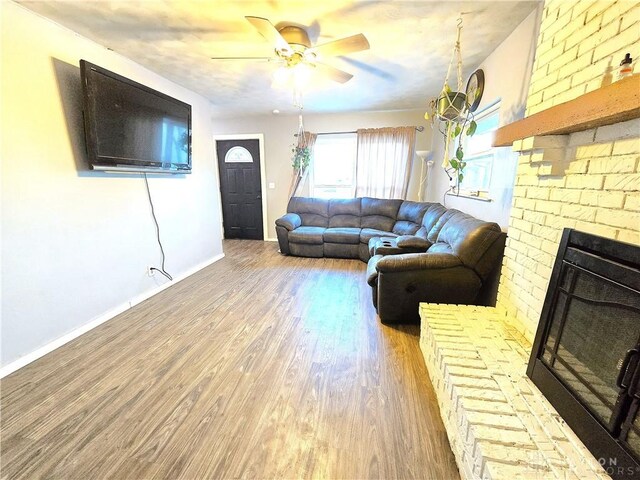 living room with ceiling fan, a fireplace, and light wood-type flooring