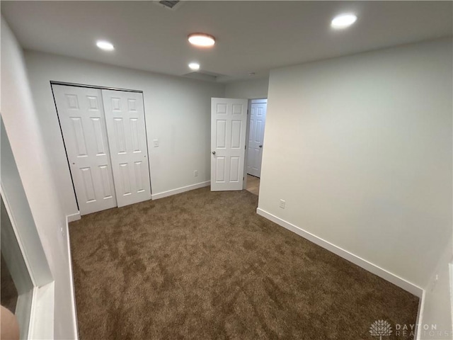 unfurnished bedroom featuring dark carpet and a closet