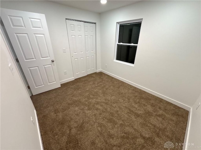 unfurnished bedroom with a closet and dark colored carpet