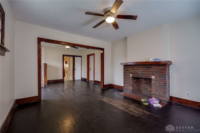 unfurnished living room with ceiling fan, a brick fireplace, and dark hardwood / wood-style flooring