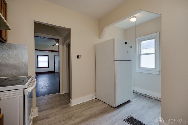 kitchen with a healthy amount of sunlight, white appliances, and light hardwood / wood-style floors