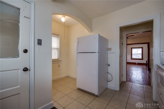 kitchen featuring light tile patterned flooring, white fridge, and stove