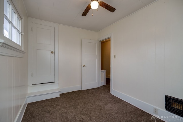 unfurnished bedroom featuring ceiling fan and dark colored carpet