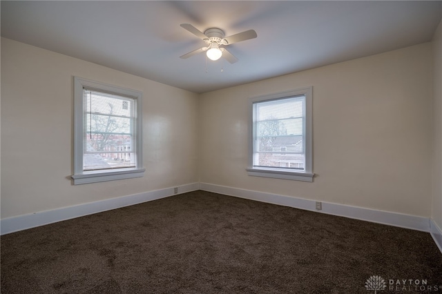 spare room with dark colored carpet and ceiling fan