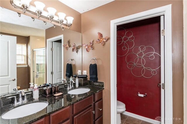 bathroom with vanity, a shower with shower door, tile patterned floors, and toilet