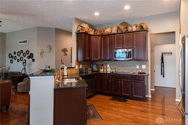 kitchen featuring sink, light hardwood / wood-style flooring, kitchen peninsula, and appliances with stainless steel finishes