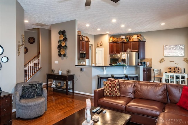 living room with hardwood / wood-style floors, a textured ceiling, and ceiling fan