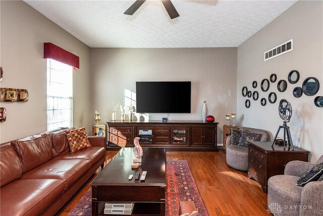 living room with wood-type flooring, ceiling fan, and a textured ceiling