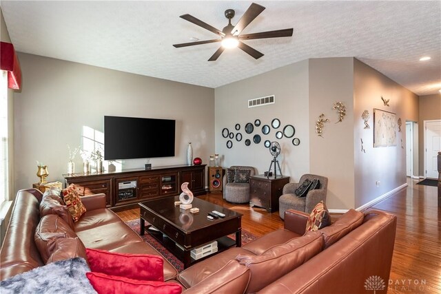 living room featuring ceiling fan, hardwood / wood-style floors, and a textured ceiling