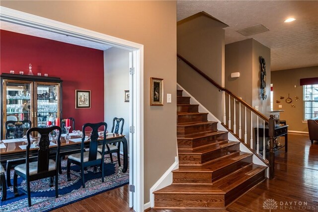 stairs with wood-type flooring and a textured ceiling