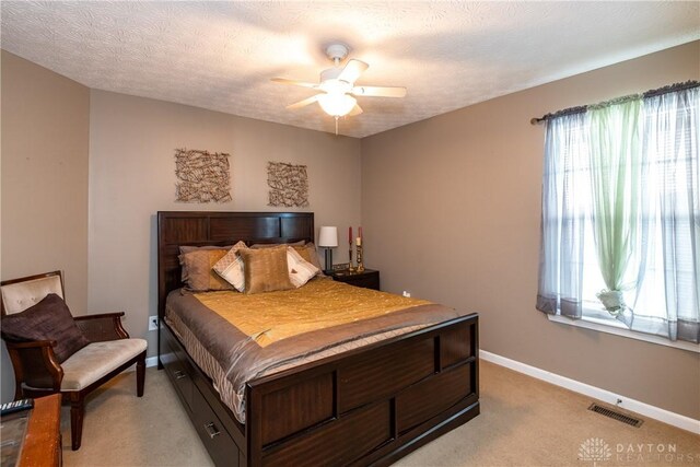 carpeted bedroom with ceiling fan and a textured ceiling