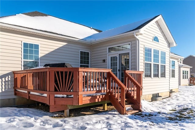 snow covered back of property with a wooden deck