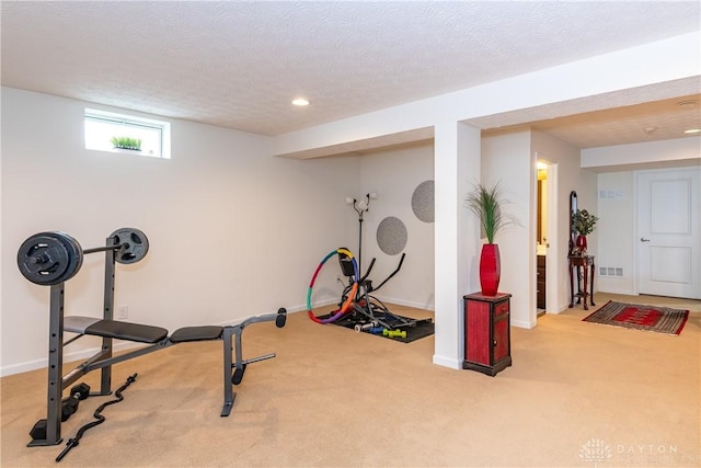 exercise room featuring light carpet and a textured ceiling