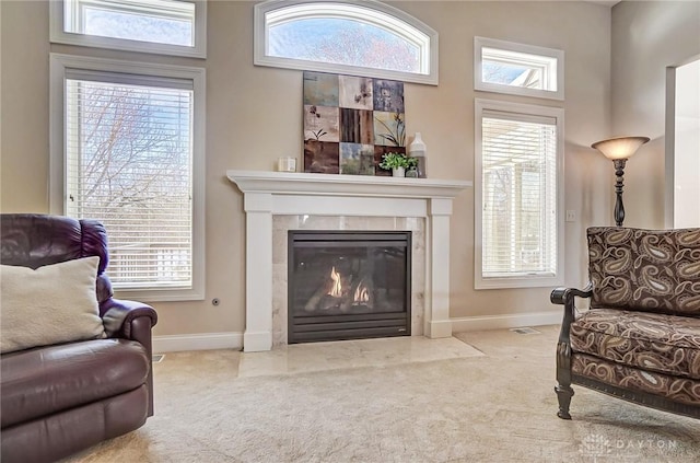 living area with a high end fireplace, plenty of natural light, and carpet floors