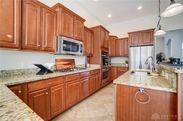 kitchen featuring light stone counters, appliances with stainless steel finishes, sink, and hanging light fixtures