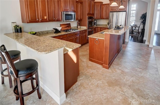 kitchen with sink, stainless steel appliances, a kitchen breakfast bar, decorative light fixtures, and kitchen peninsula