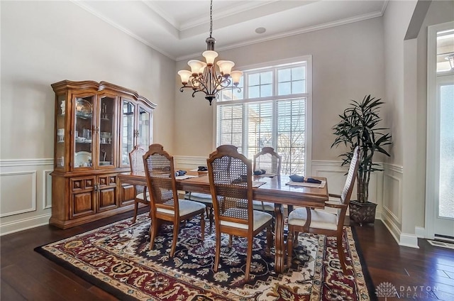 dining room featuring a raised ceiling, ornamental molding, dark hardwood / wood-style floors, and an inviting chandelier