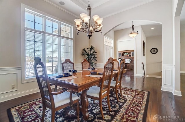 dining space featuring dark hardwood / wood-style flooring, crown molding, and an inviting chandelier