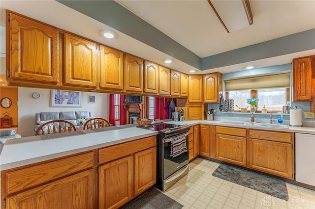 kitchen with stainless steel range with electric stovetop, sink, white dishwasher, and kitchen peninsula